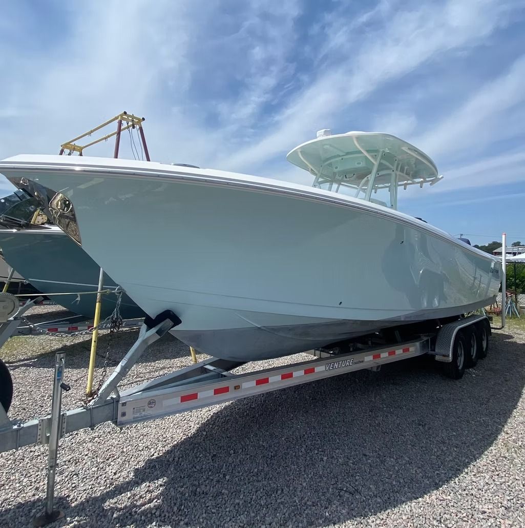 Large white boat on a trailer, outdoors with a blue sky.