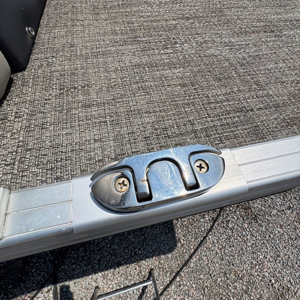 Metal boat cleat screwed onto an aluminum surface, angled view.