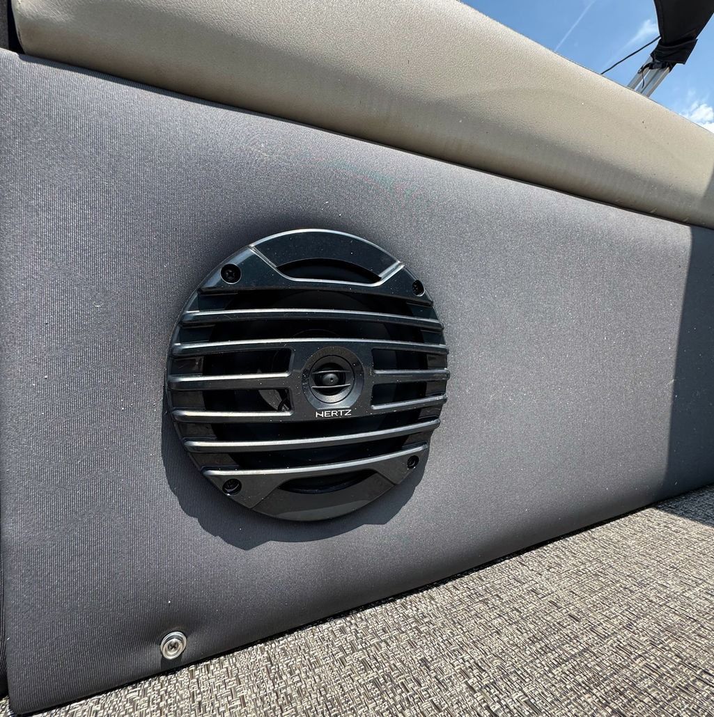 Black speaker mounted on gray upholstered boat seat.