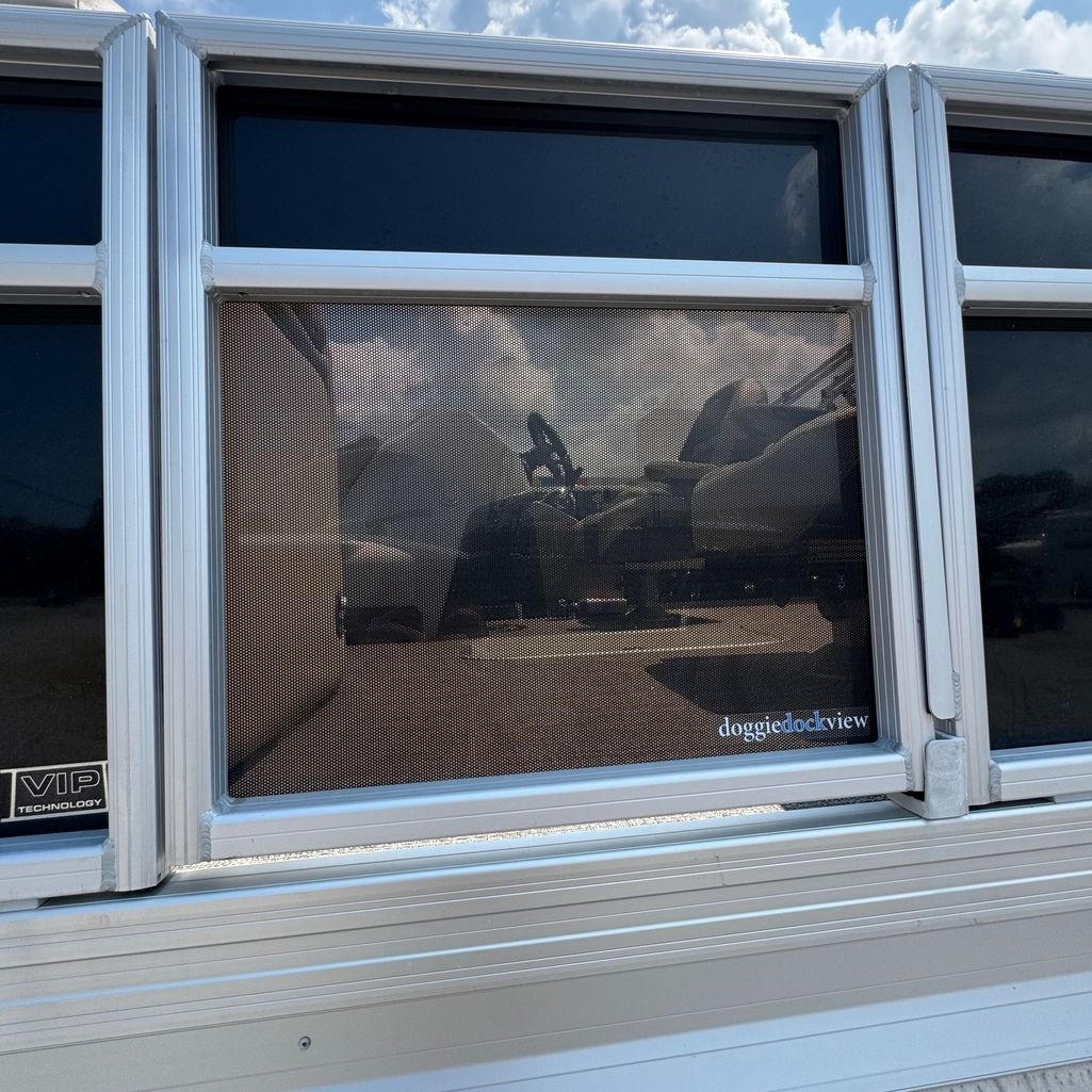 Aluminum boat with a wicker-style screen and tinted windows. Outdoors, sunny day.