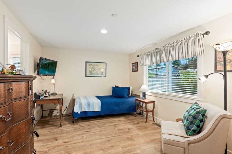 A bedroom with a single bed , chair , dresser and television.