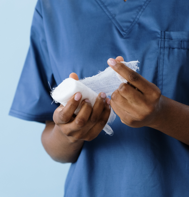 A person in a blue scrub is holding a piece of bandage