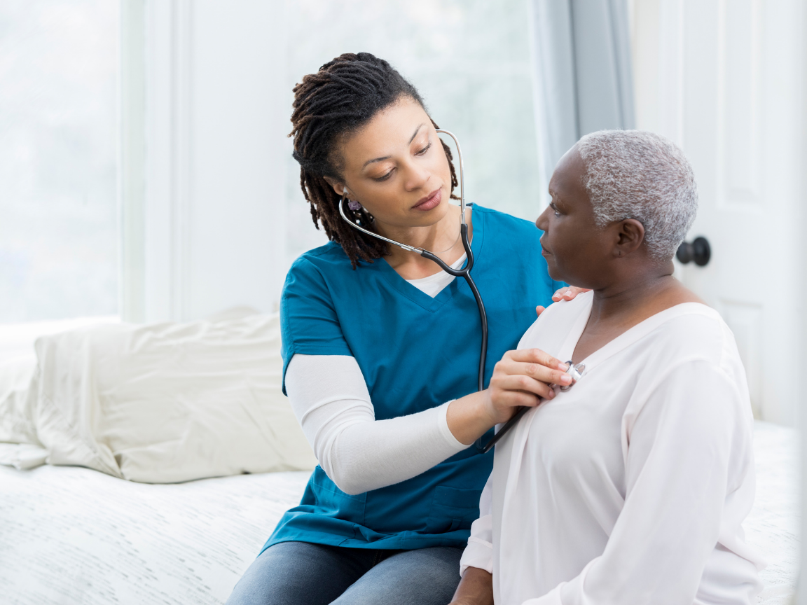 A nurse is listening to an older woman 's heartbeat with a stethoscope.