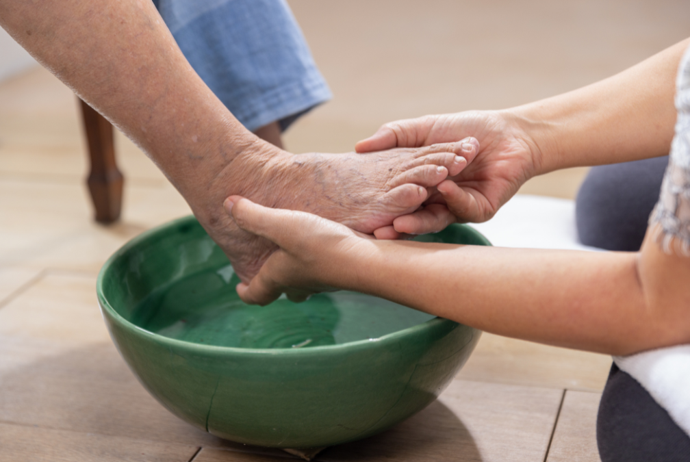 A person is washing another person 's feet in a bowl of water.