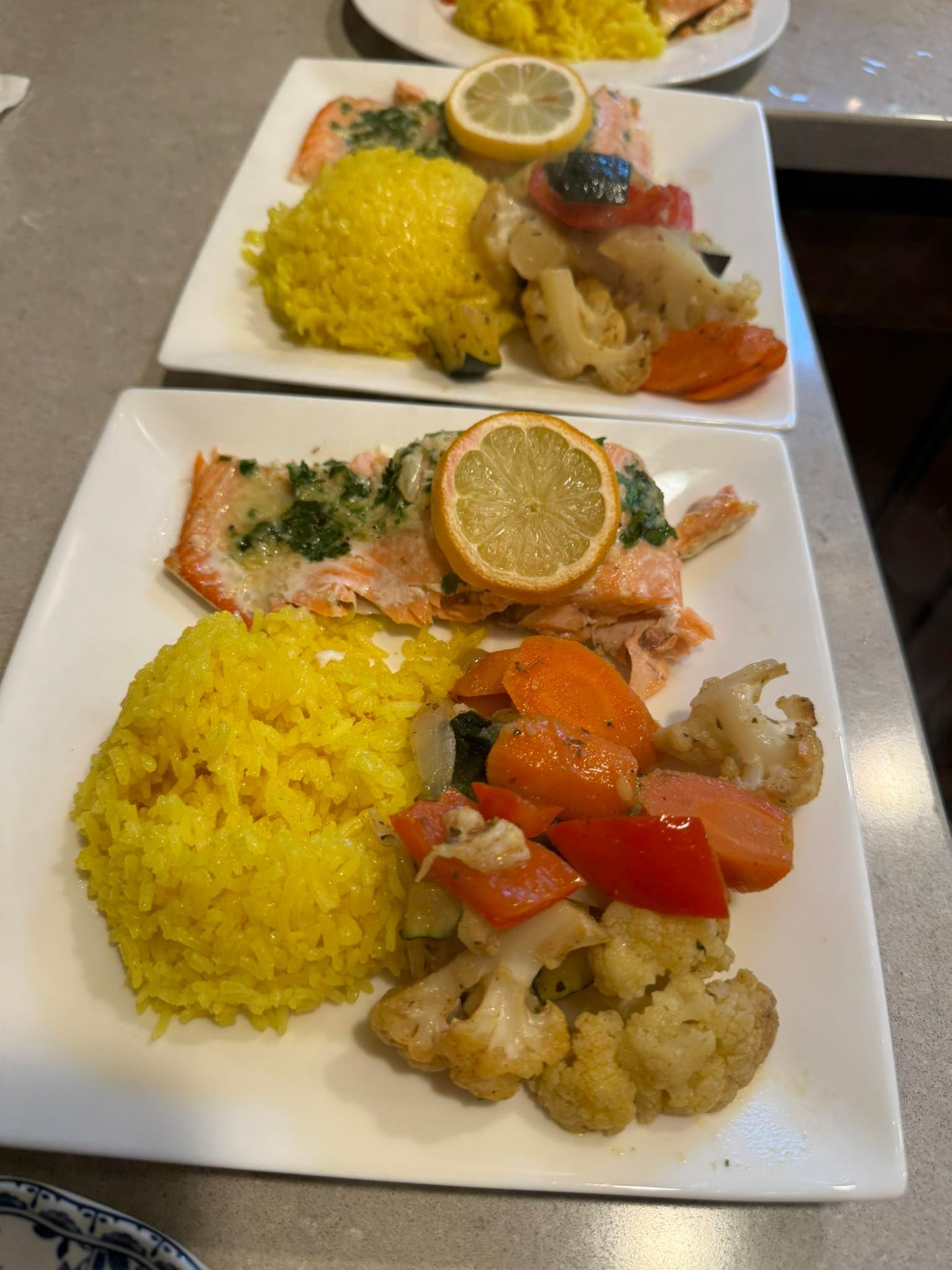 Three plates of food are on a table including rice and vegetables.