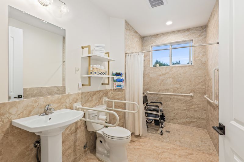 A bathroom with a toilet , sink , and wheelchair.