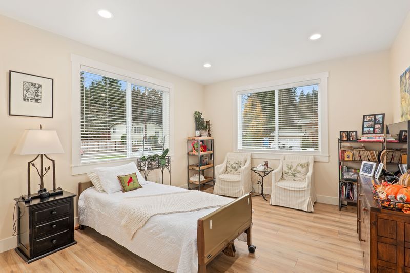 A bedroom with a bed , chairs , nightstand and dresser.