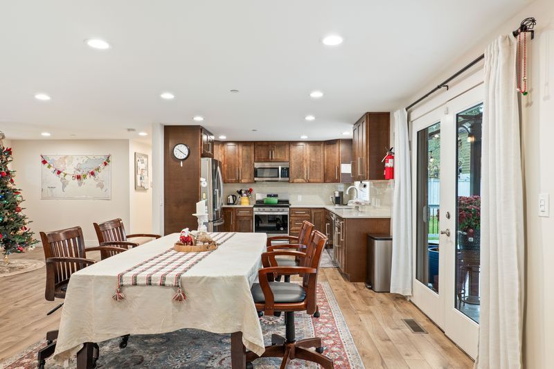 A dining room table and chairs in a kitchen with a christmas tree in the background.