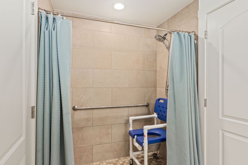 A handicapped shower with a blue chair in it.
