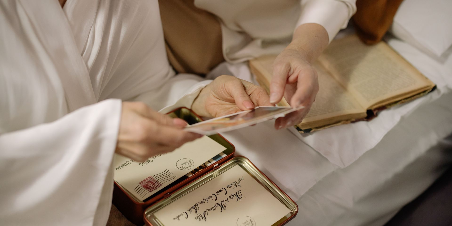 A woman is sitting on a bed holding a piece of paper.