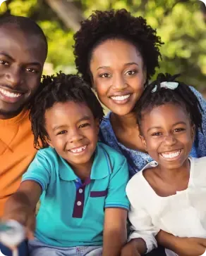 A family is posing for a picture together and smiling for the camera.