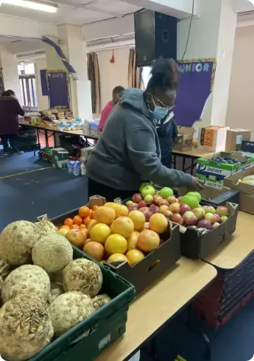 A woman is standing in front of a table full of fruits and vegetables.