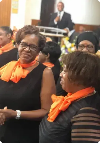 A group of women wearing orange scarves are standing in a room.