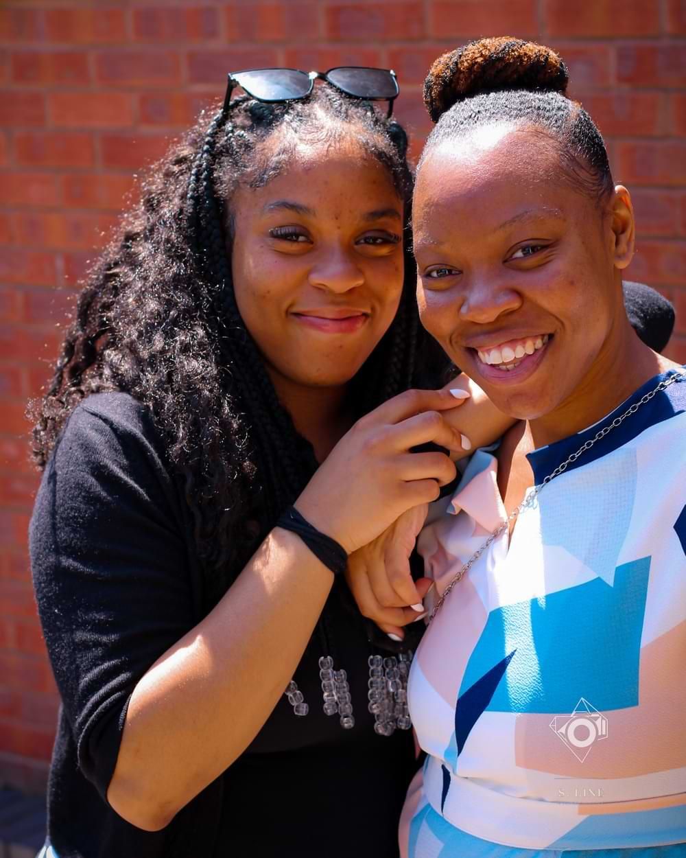 Two women posing for a picture with one wearing sunglasses