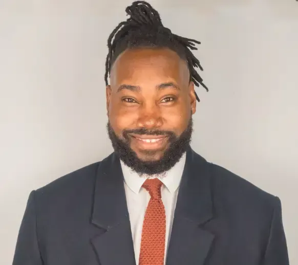 A man with dreadlocks is wearing a suit and tie.