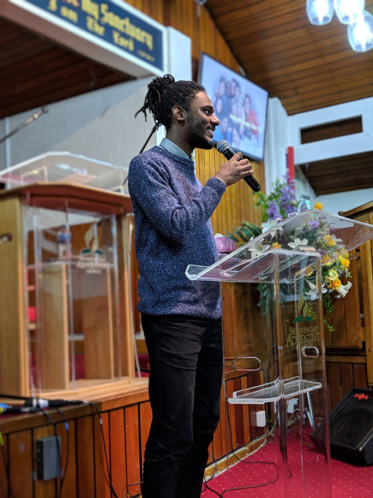 A man is standing at a podium speaking into a microphone.