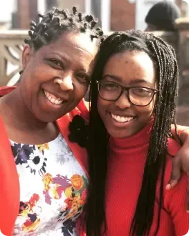 A woman and a girl are posing for a picture and smiling for the camera.