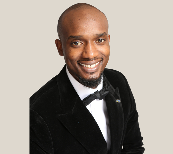 A man with a beard is wearing a blue jacket and a white shirt.