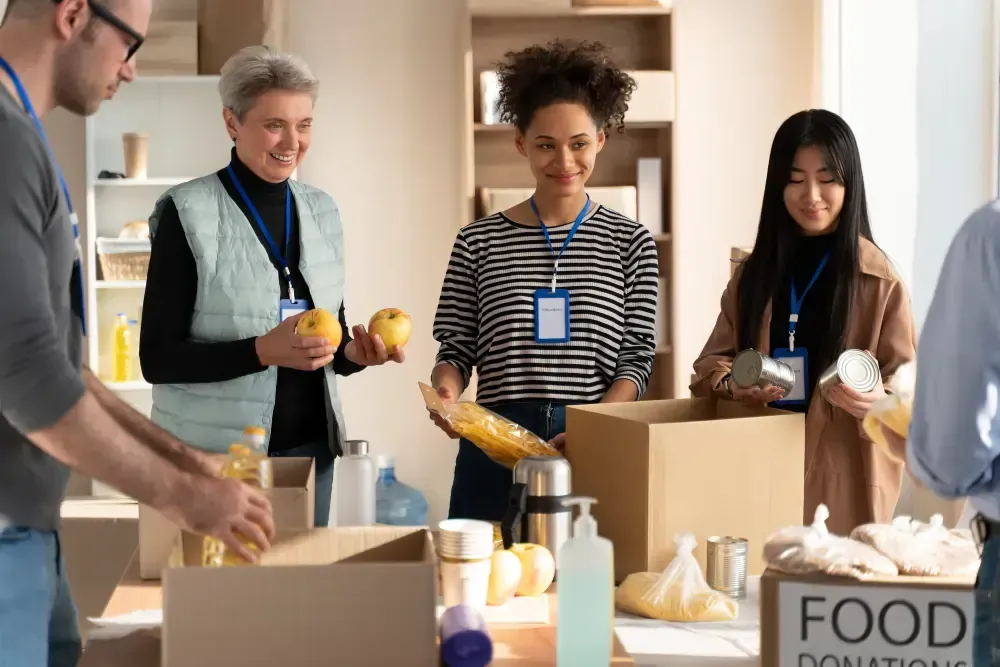 A group of people are standing around a table filled with boxes of food.