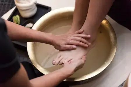 A person is giving a foot massage in a bowl of water.