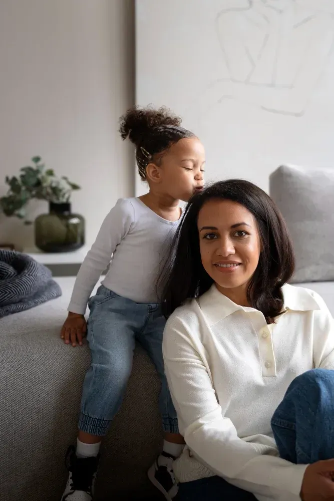 A woman and a little girl are sitting on a couch.
