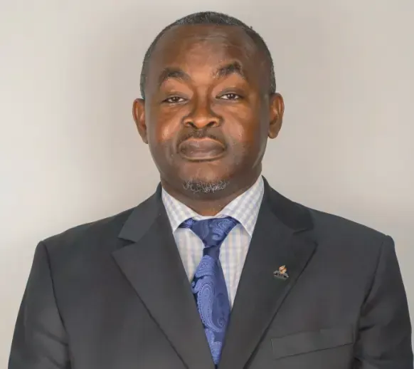 A man in a suit and tie is standing in front of a white wall.