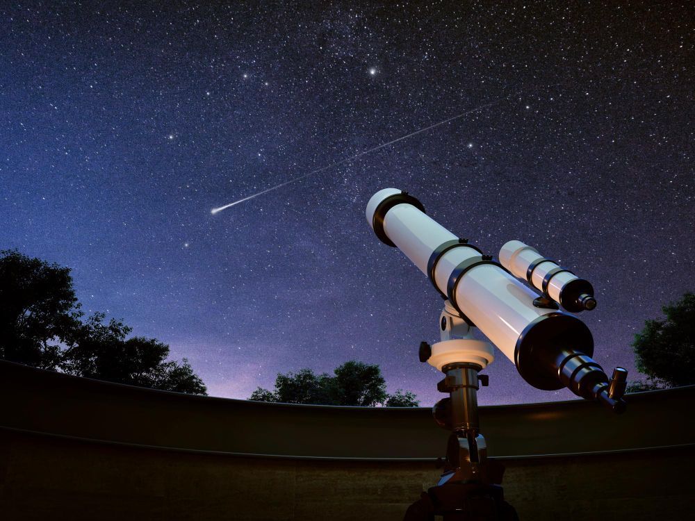 A person is looking through a telescope at the night sky