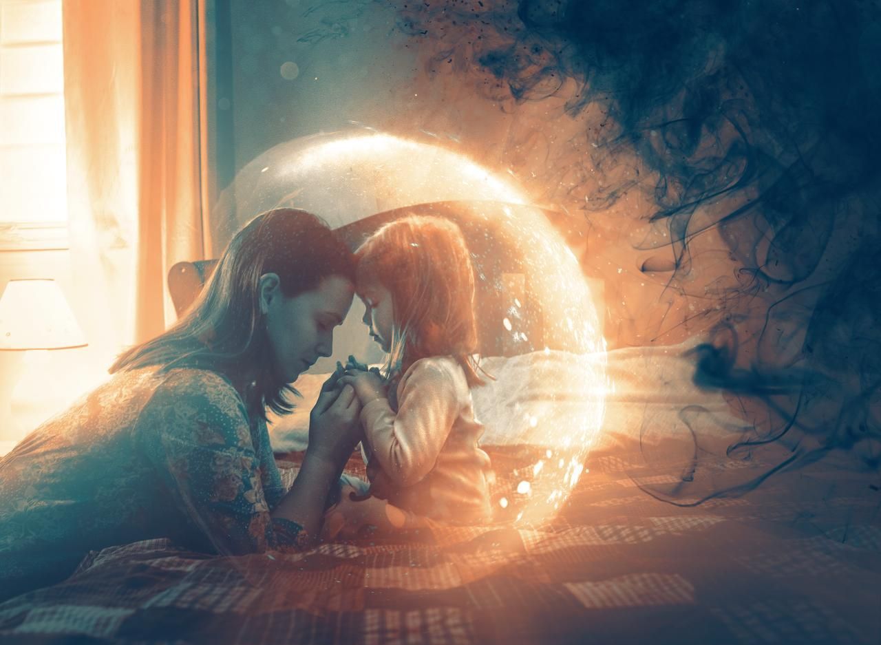 A woman and a child are sitting on a bed in front of a light bulb.