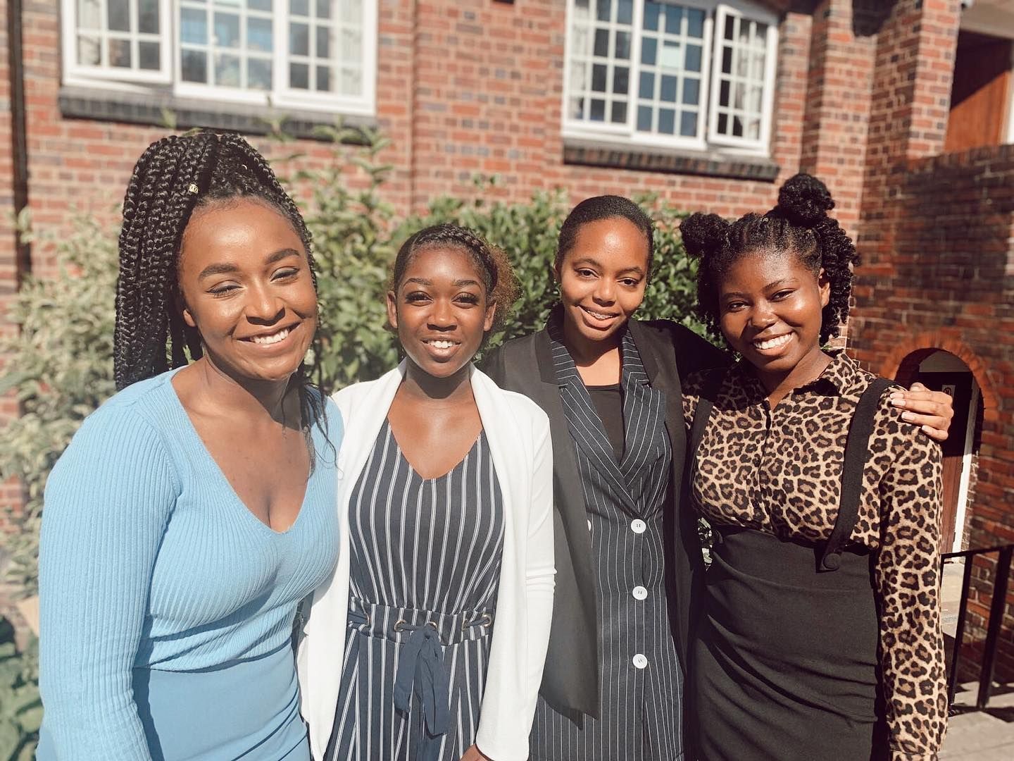 A group of young women are posing for a picture in front of a brick building.