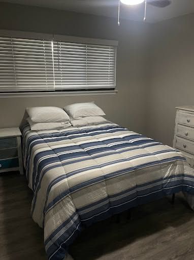 Neatly made bedroom with striped bedspread, window blinds, ceiling fan, and white dresser