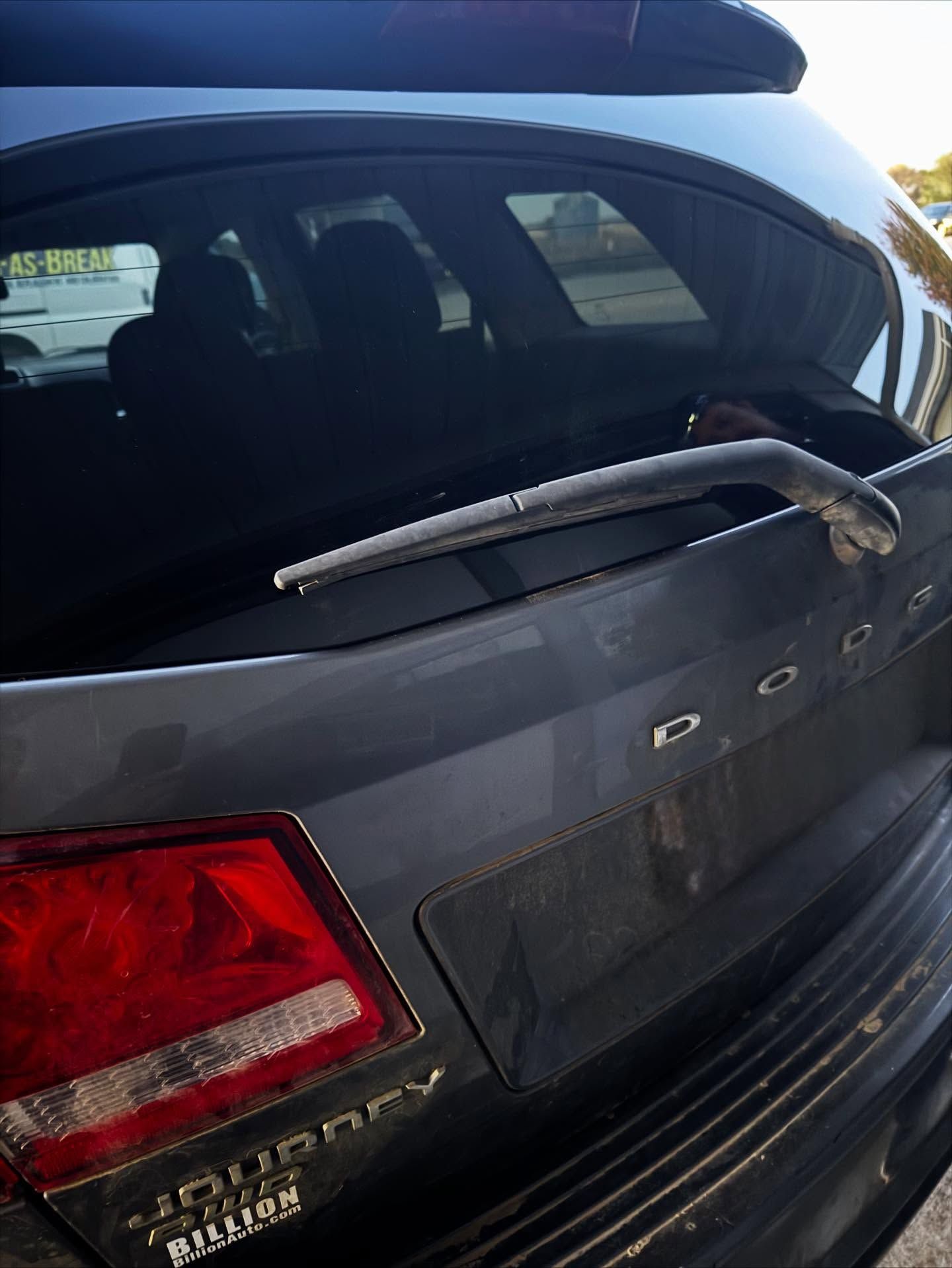 Rear view of a grey Dodge Journey SUV featuring a rear windshield wiper and a dealership sticker.