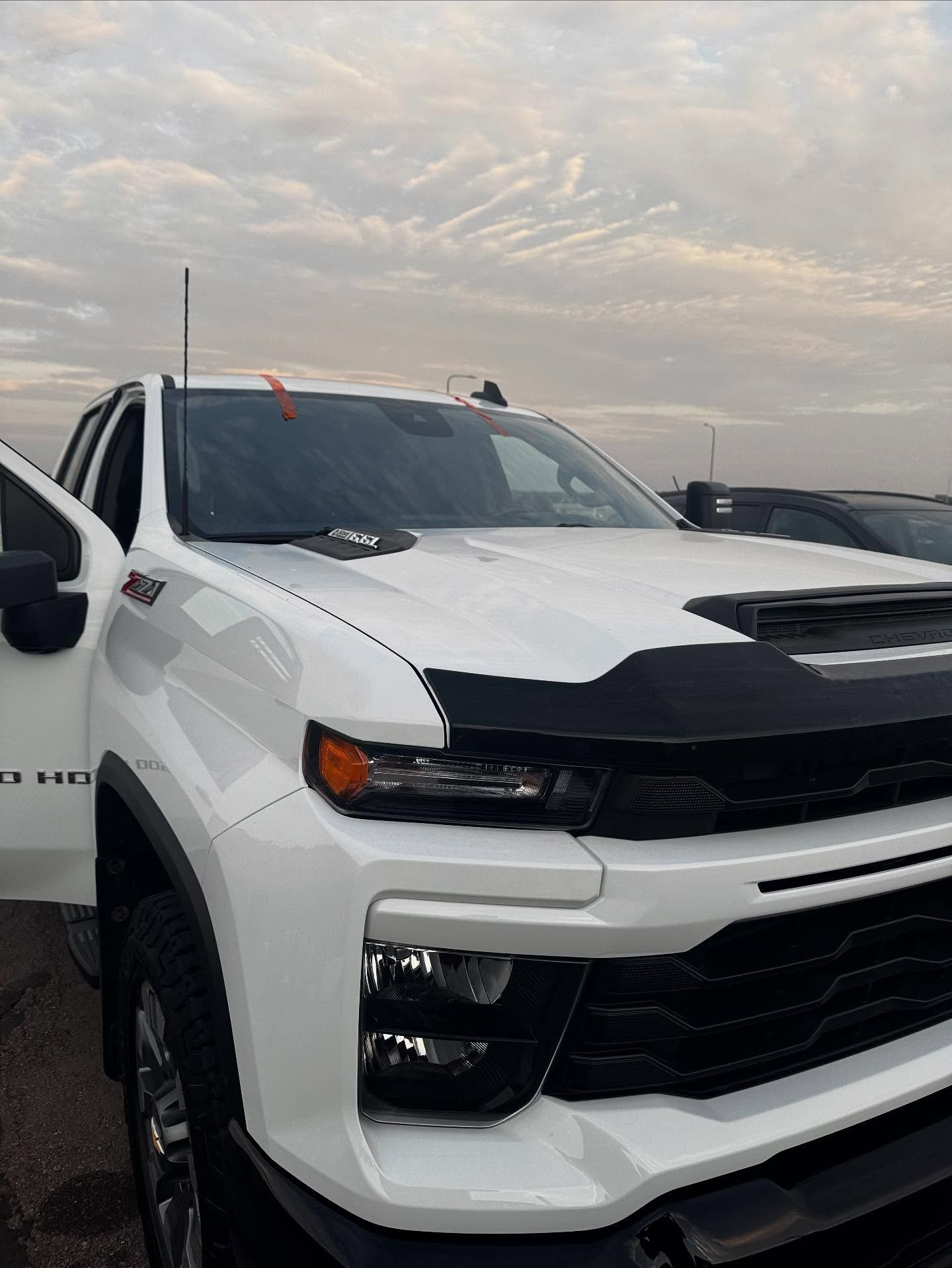 A white Chevrolet Silverado pickup truck parked outdoors under a cloudy sky.