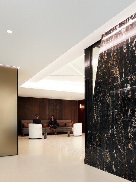 Two people sit on a couch in a room with a black wall