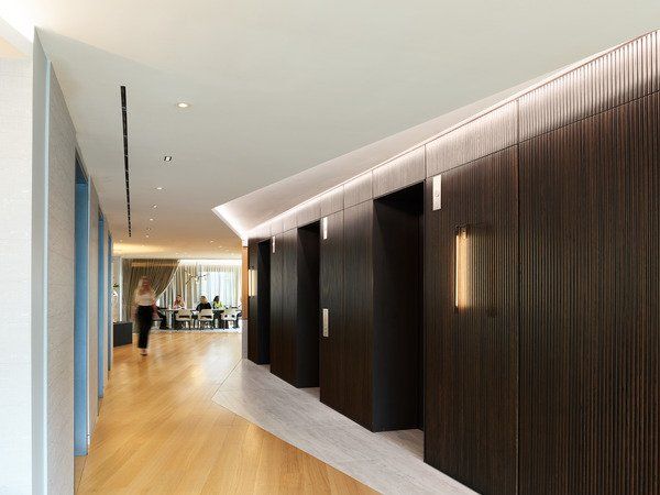 A long hallway with wooden floors and elevators in a building