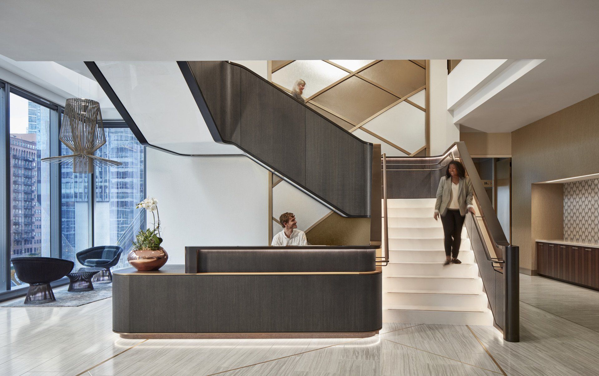 A woman is walking down a set of stairs next to a reception desk.