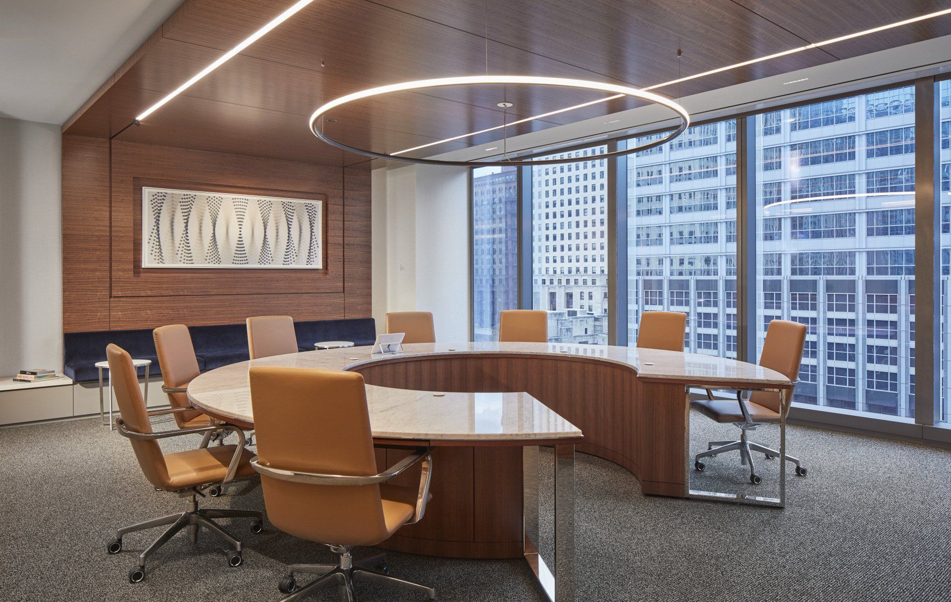 A conference room with a round table and chairs and a large window.