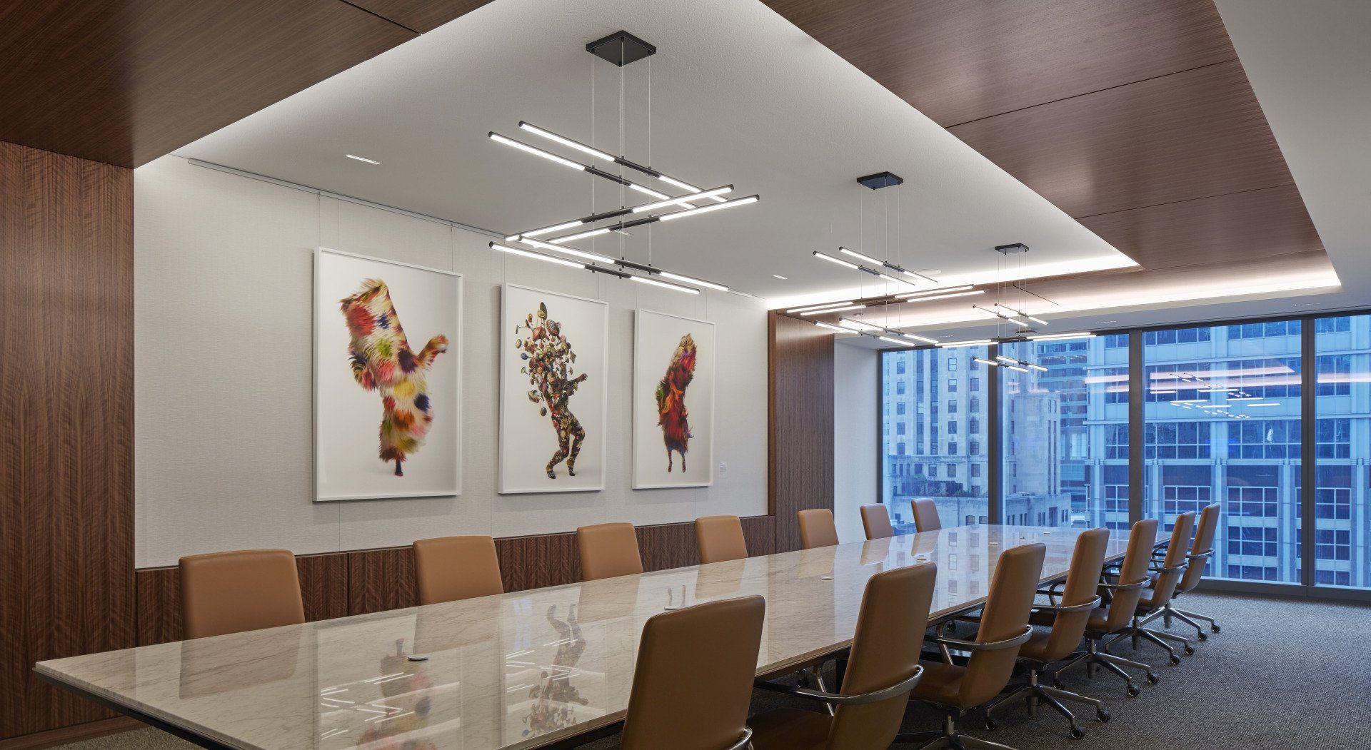 A conference room with a long table and chairs and paintings on the wall.