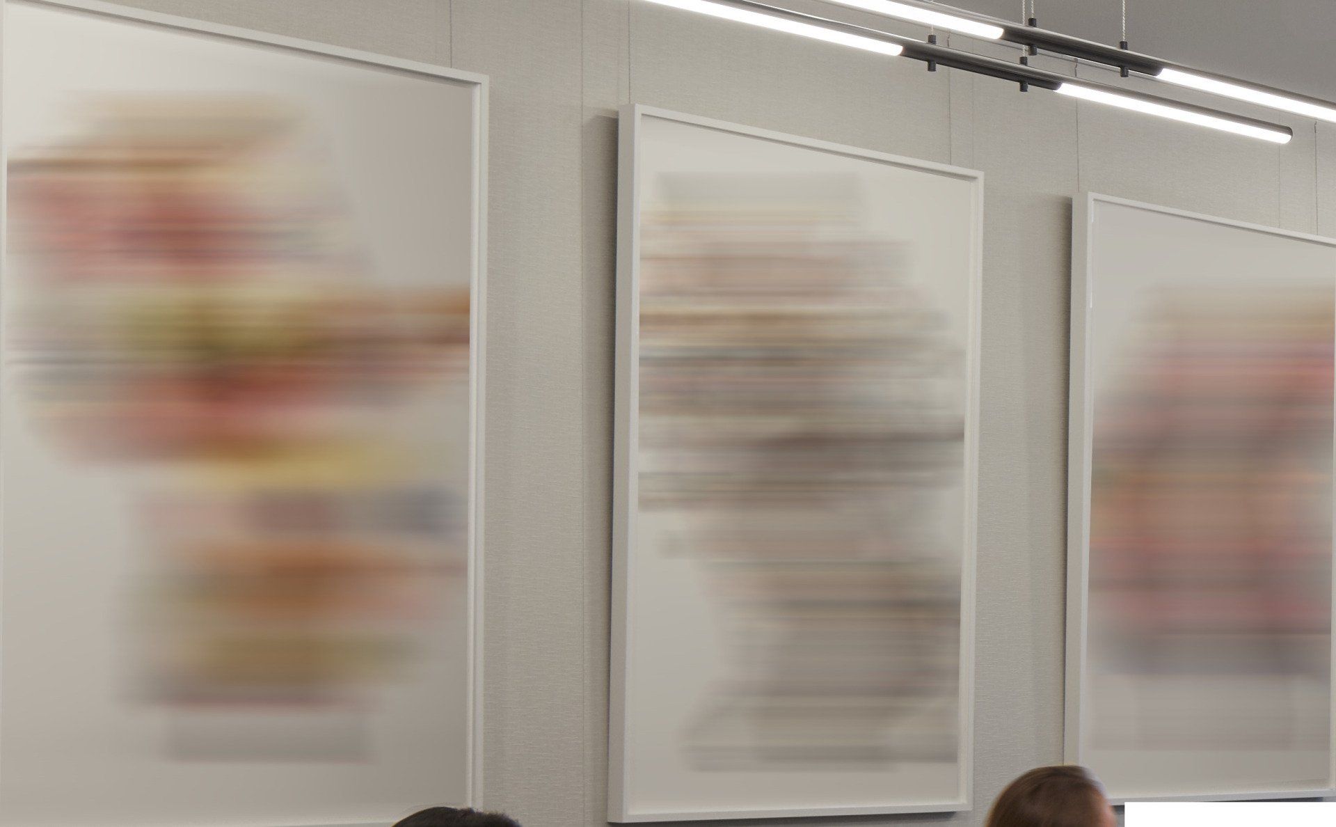 Three paintings are hanging on a wall in a room.