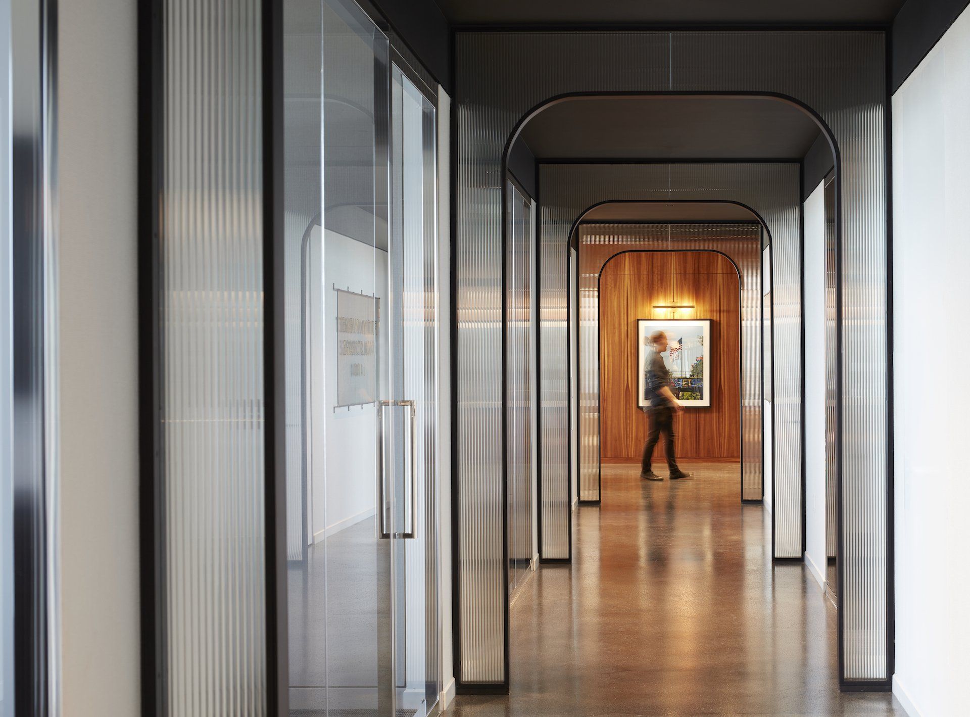 A man is standing in a hallway with a picture on the wall.