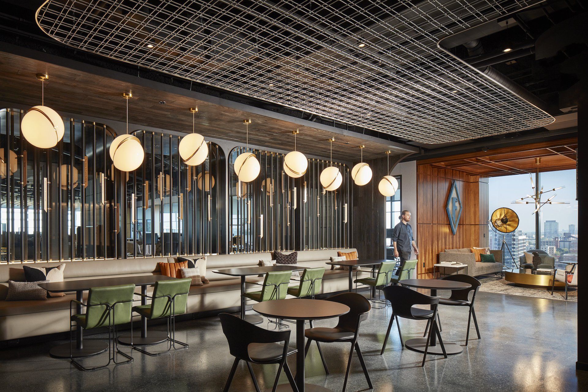A man is standing in a restaurant with tables and chairs.
