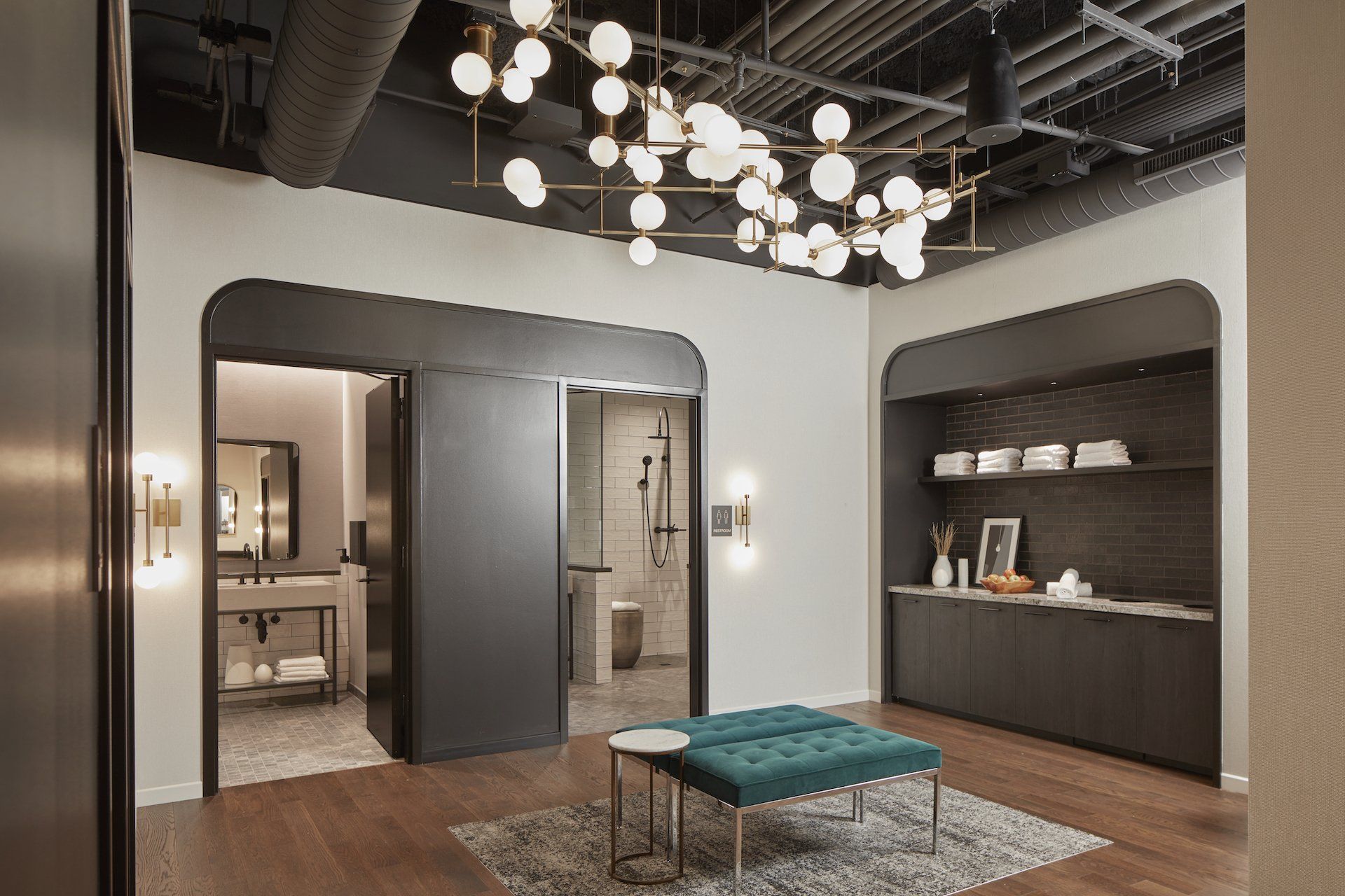 A living room with a blue ottoman and a chandelier hanging from the ceiling.