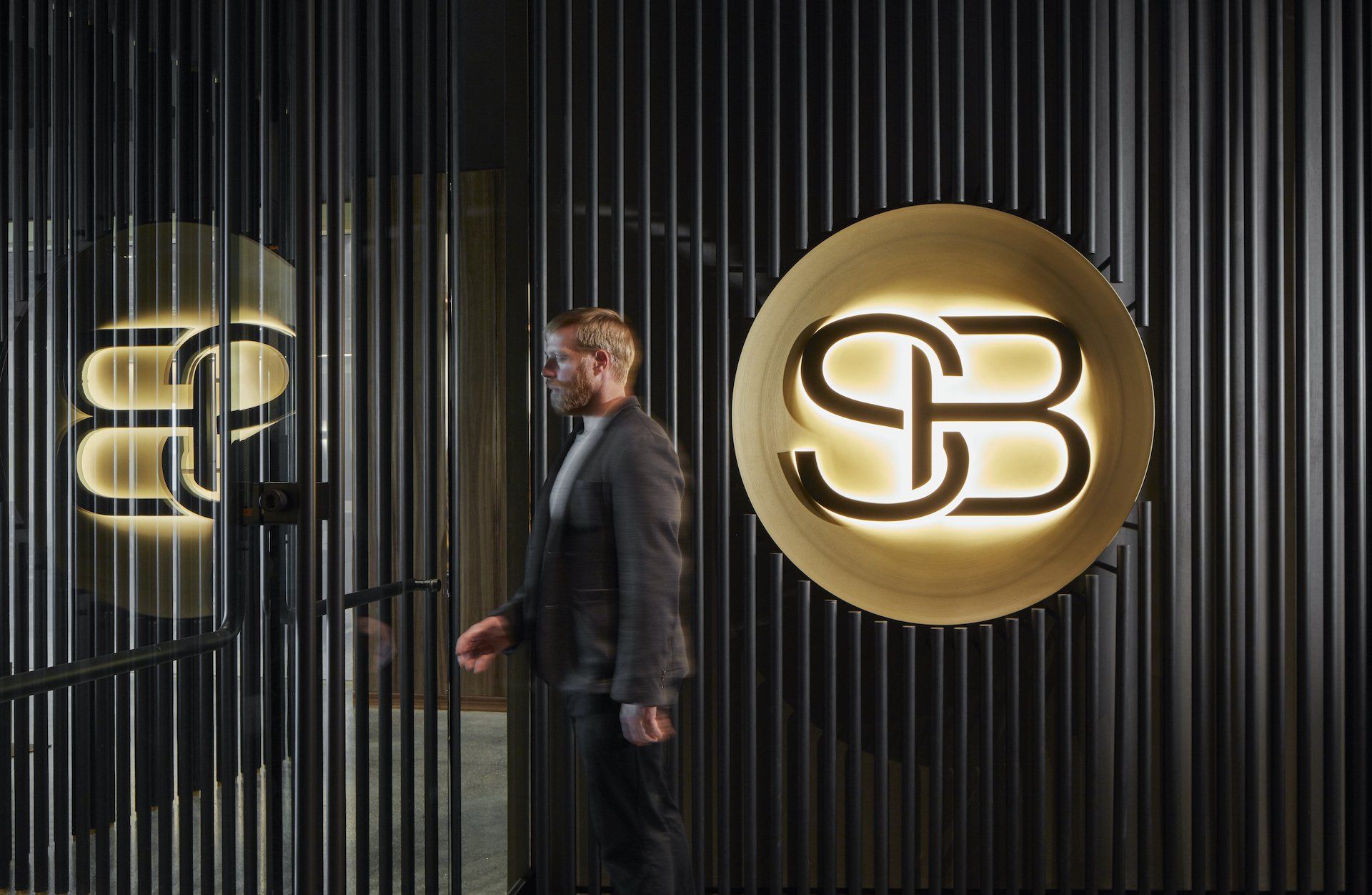 A man in a suit is standing in front of a sign that says sb.
