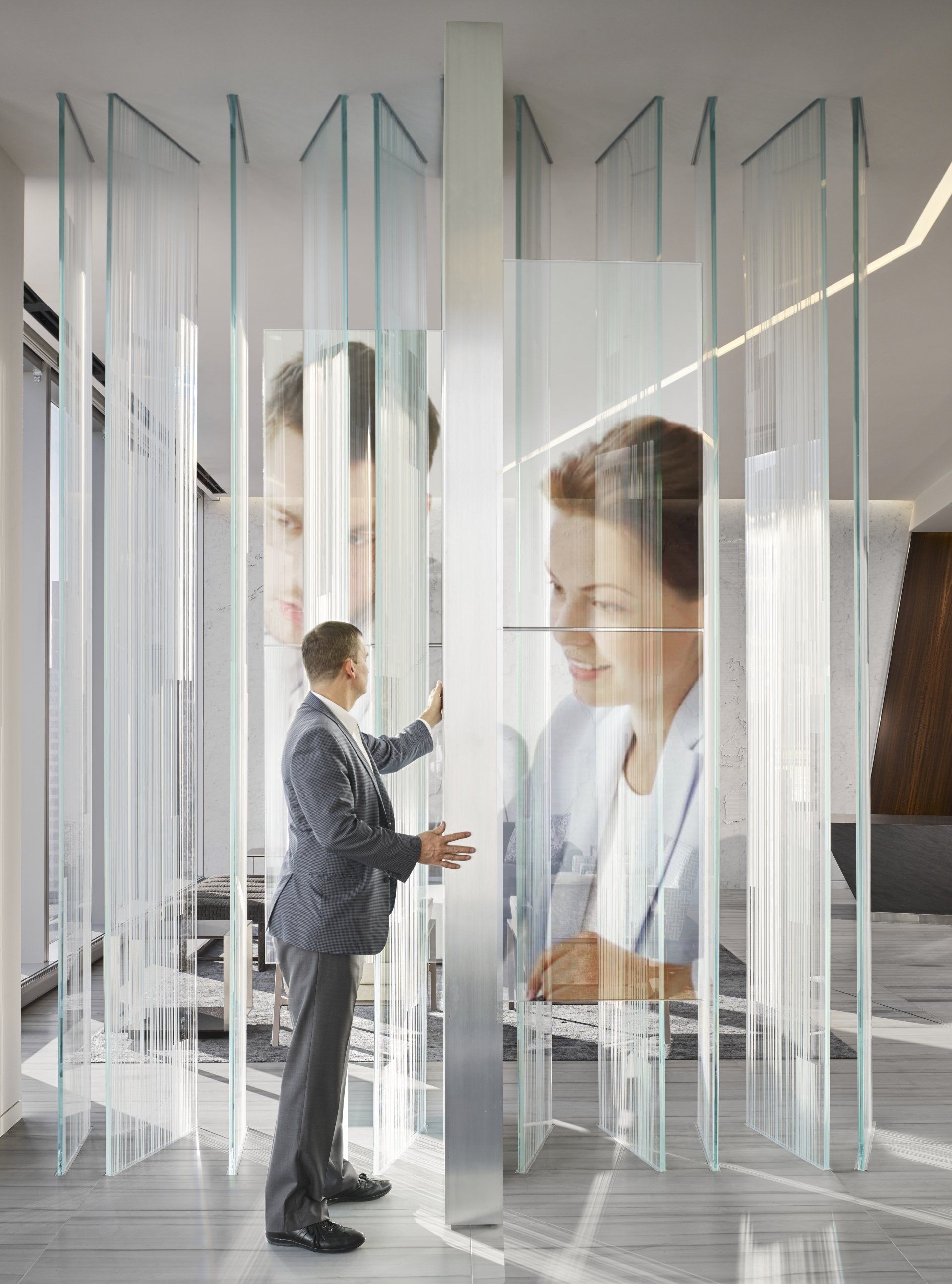 A man in a suit is standing in front of a glass wall.