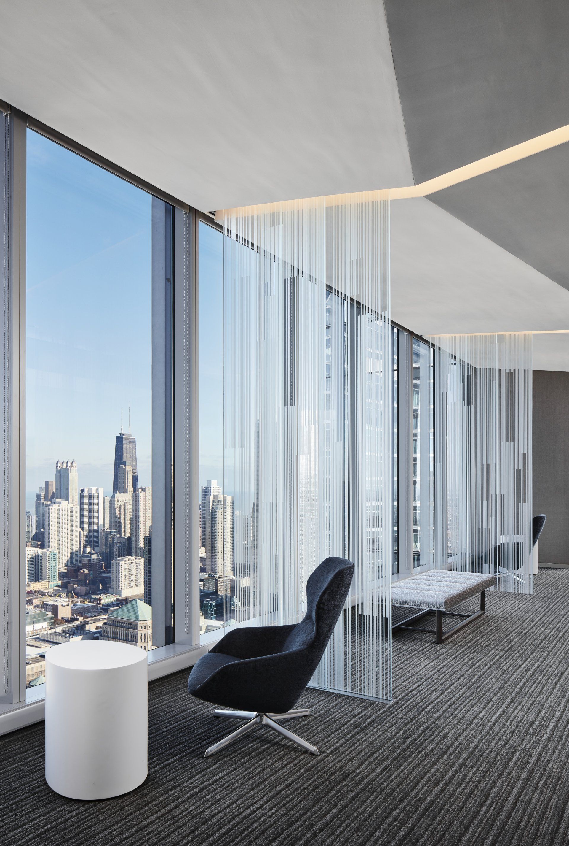 There is a chair in the middle of the room with a view of the city.