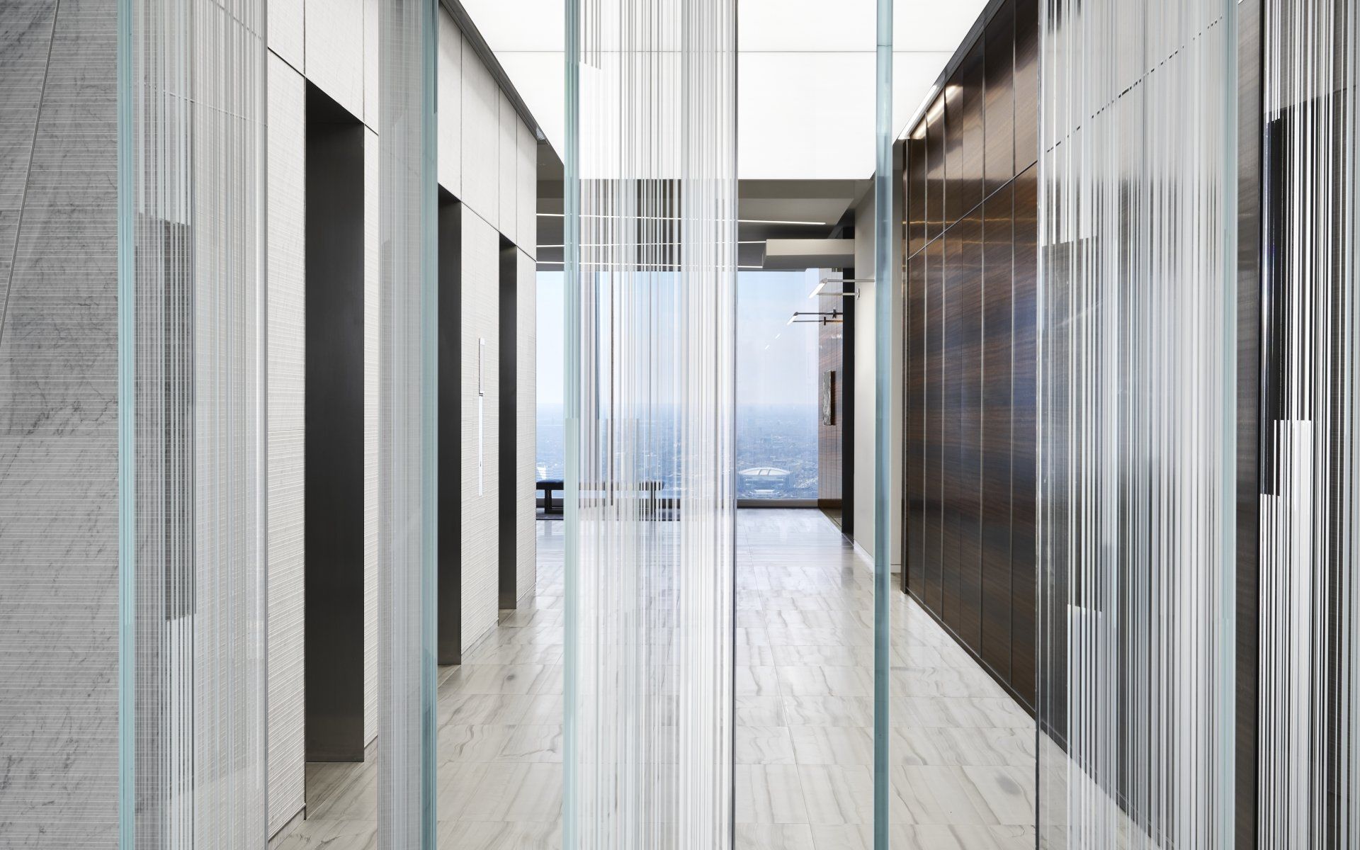 A hallway with a lot of glass walls and a large window.