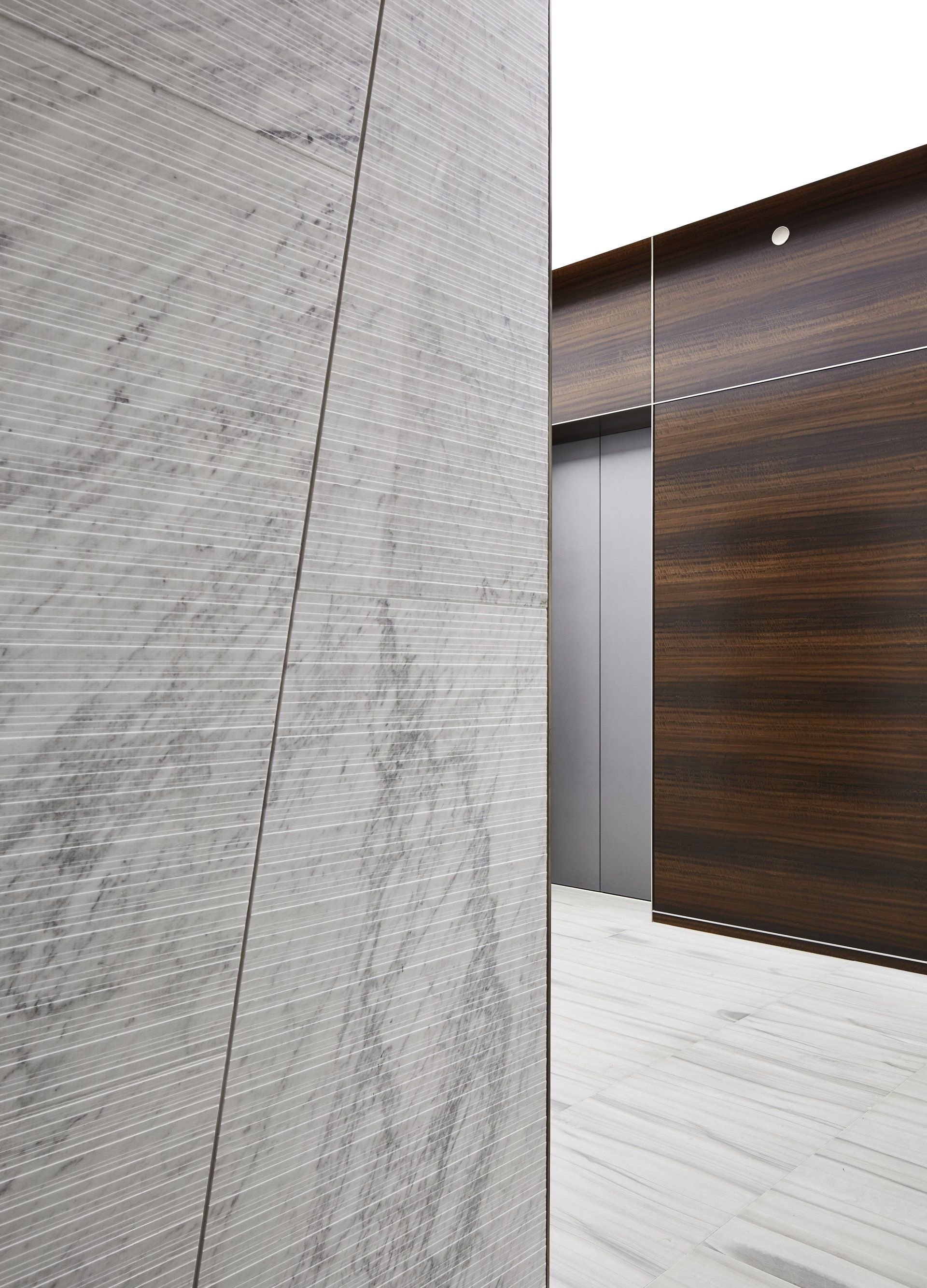 A building with a marble wall and a wooden wall next to an elevator.