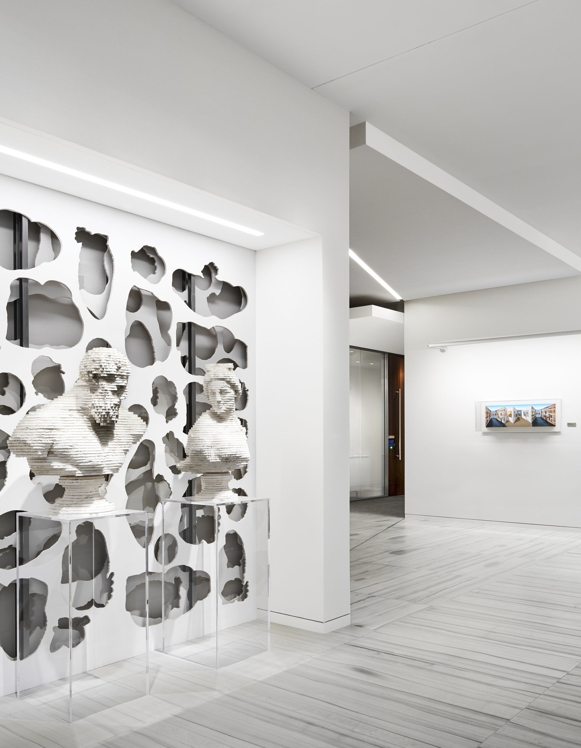 A black and white photo of a hallway with a sculpture on the wall.