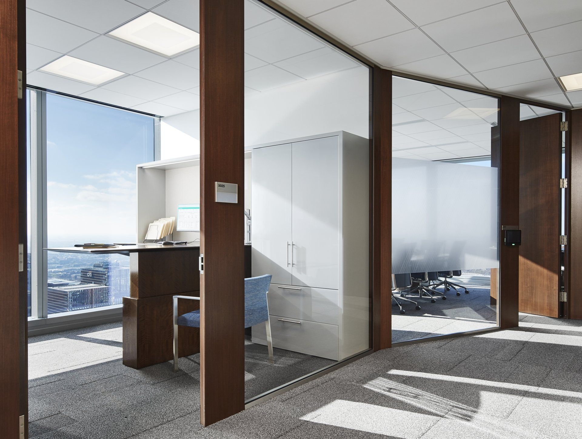 An office with a desk and chairs and a large window