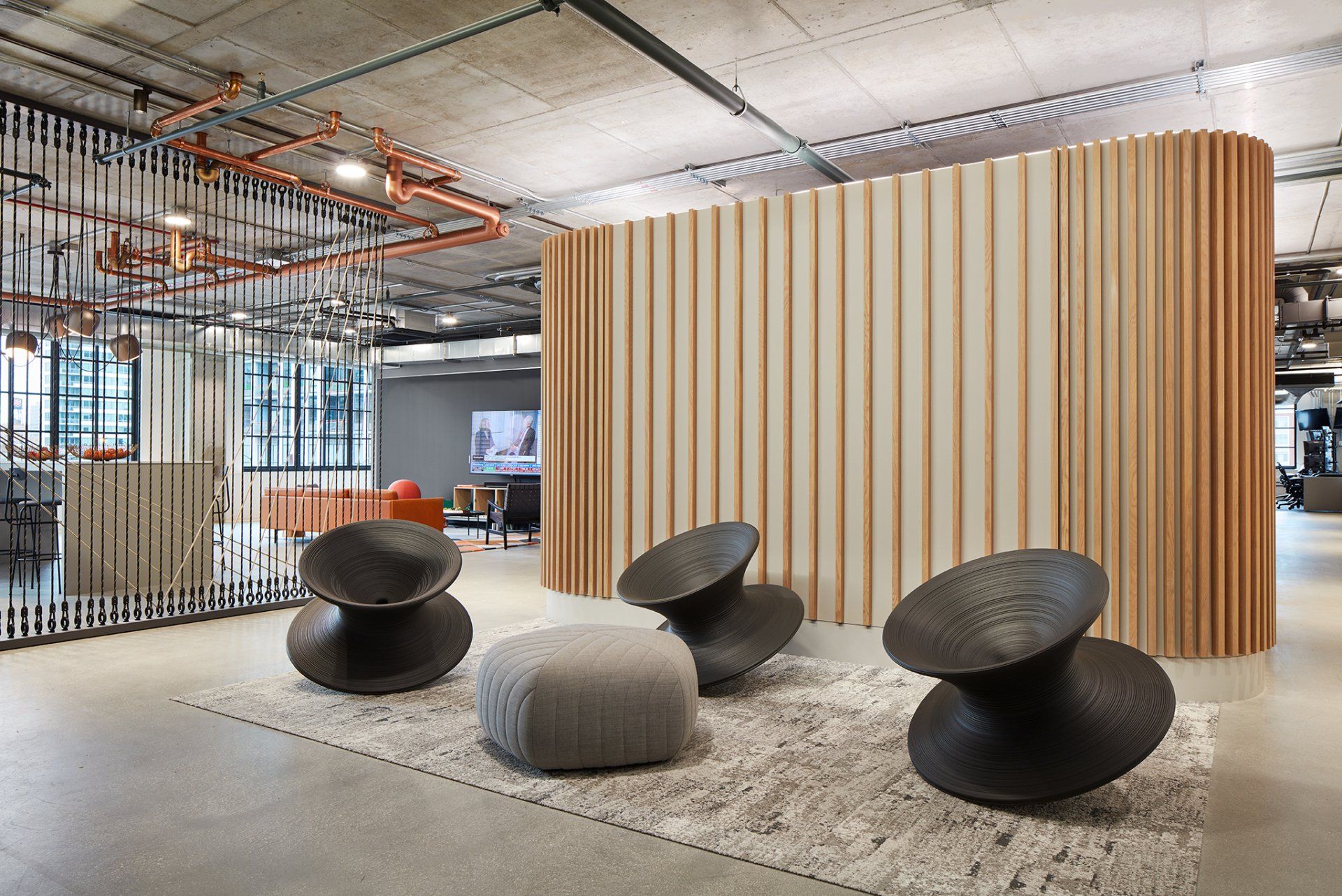 A room with chairs and ottomans in front of a wooden wall.