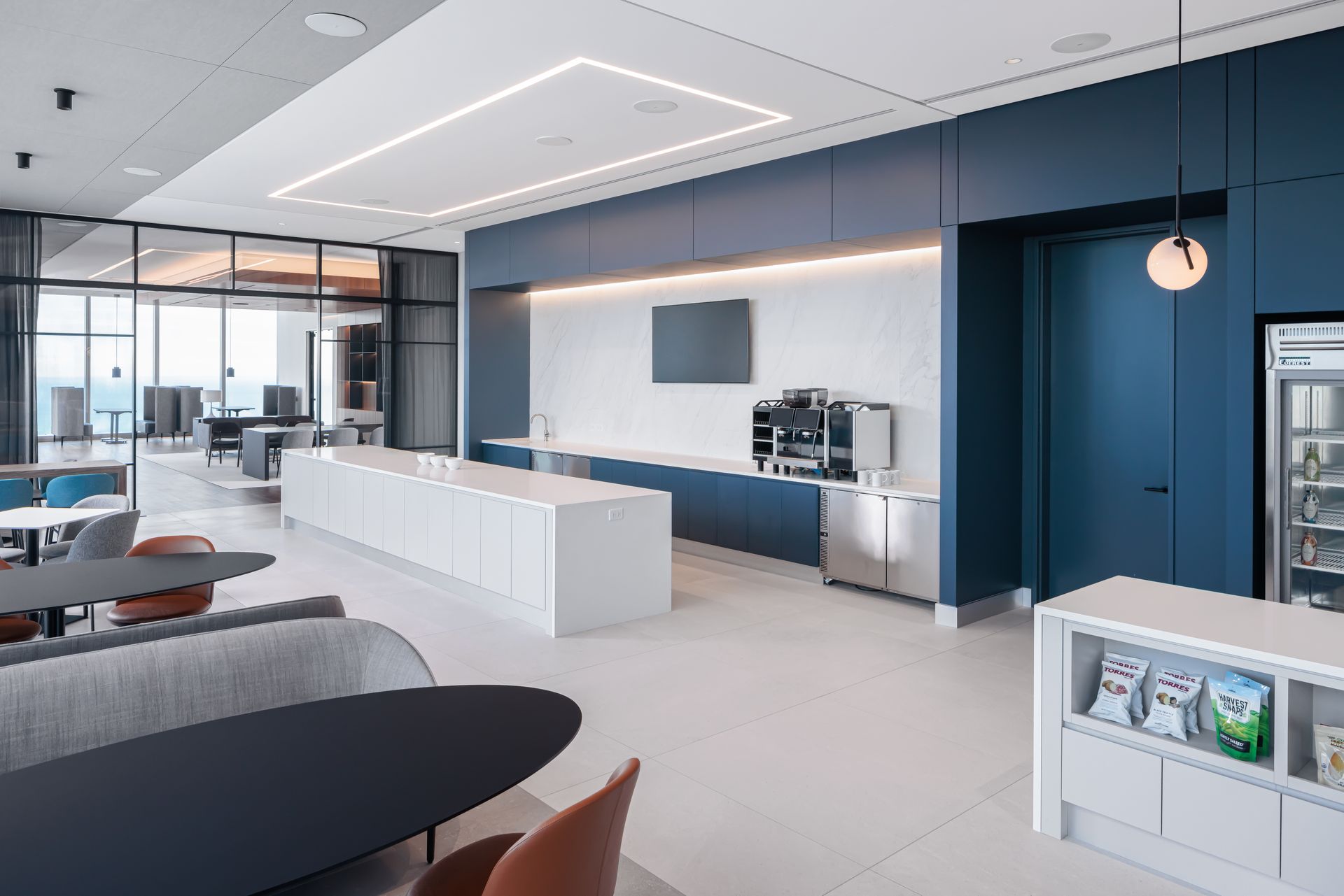 A large room with tables , chairs , and a refrigerator.